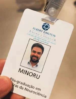 Crachá de aluno da pós-graduação em Neurociência do Instituto Israelita de Ensino e Pesquisa Albert Einstein, com a foto e o nome Minoru Crachá de aluno da pós-graduação em Neurociência do Instituto Israelita de Ensino e Pesquisa Albert Einstein, com a foto e o nome Minoru