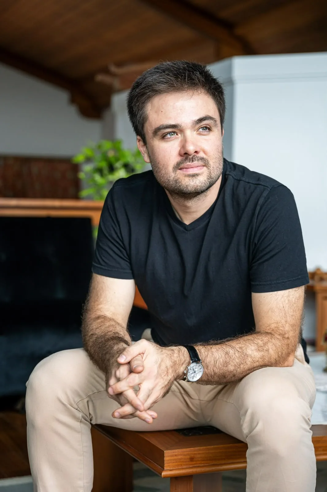 Minoru Raphael sentado, de camiseta preta e mãos entrelaçadas, olhando para o lado num ambiente com teto de madeira Minoru Raphael sentado, de camiseta preta e mãos entrelaçadas, olhando para o lado num ambiente com teto de madeira
